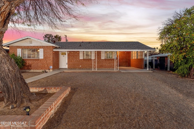 ranch-style house with roof with shingles and brick siding