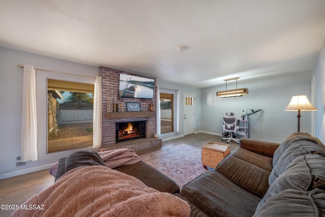 living room featuring a fireplace, baseboards, and wood finished floors