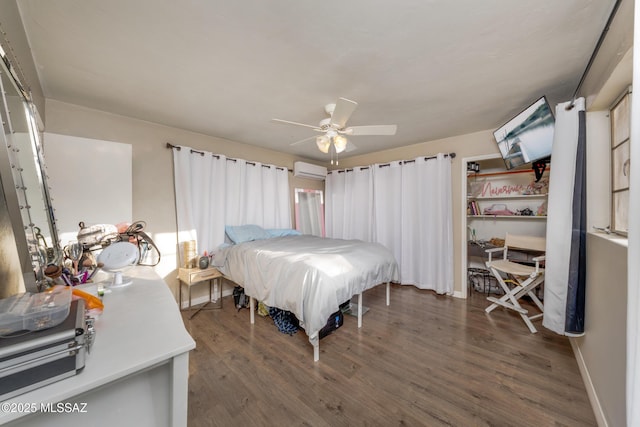 bedroom featuring ceiling fan, baseboards, dark wood finished floors, and an AC wall unit