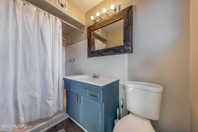 full bath featuring visible vents, a shower with shower curtain, toilet, vanity, and tile walls