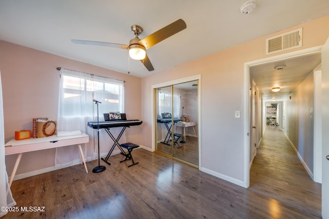 home office featuring a ceiling fan, wood finished floors, visible vents, and baseboards