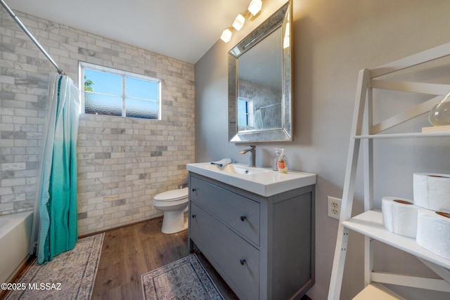 bathroom featuring toilet, shower / bathtub combination with curtain, wood finished floors, and vanity