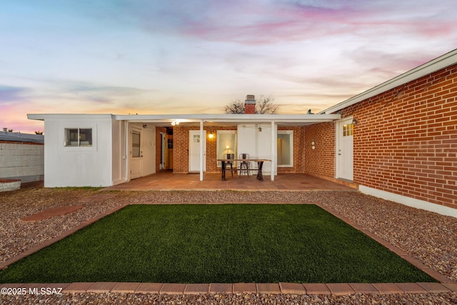 back of property featuring a patio area, brick siding, and a chimney