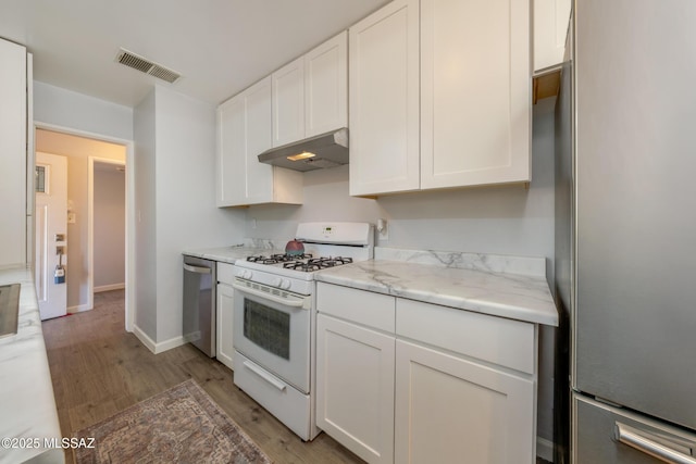 kitchen with under cabinet range hood, stainless steel appliances, visible vents, white cabinets, and light wood finished floors