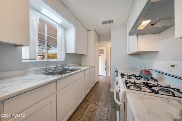 kitchen featuring white gas stove, a sink, visible vents, white cabinetry, and range hood