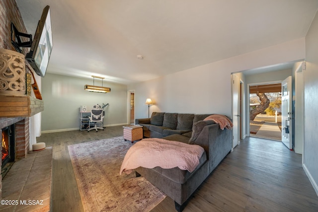 living room featuring a brick fireplace, dark wood finished floors, and baseboards