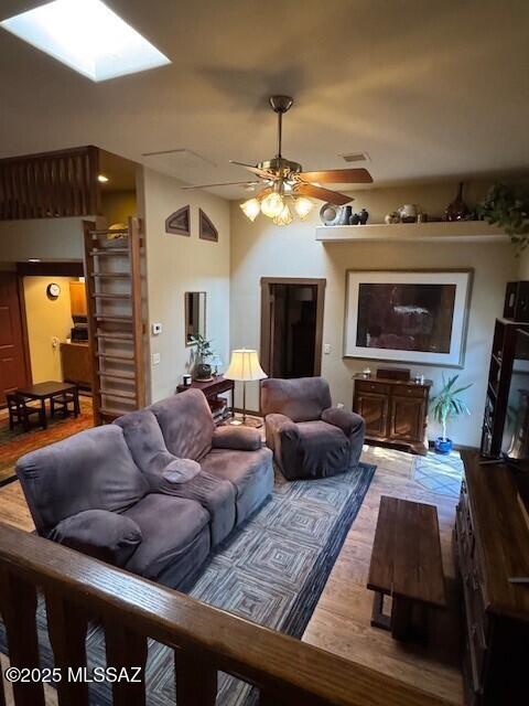 living room featuring visible vents, a skylight, light wood-style flooring, and a ceiling fan