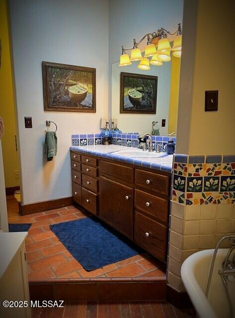 bathroom featuring a soaking tub, vanity, and baseboards