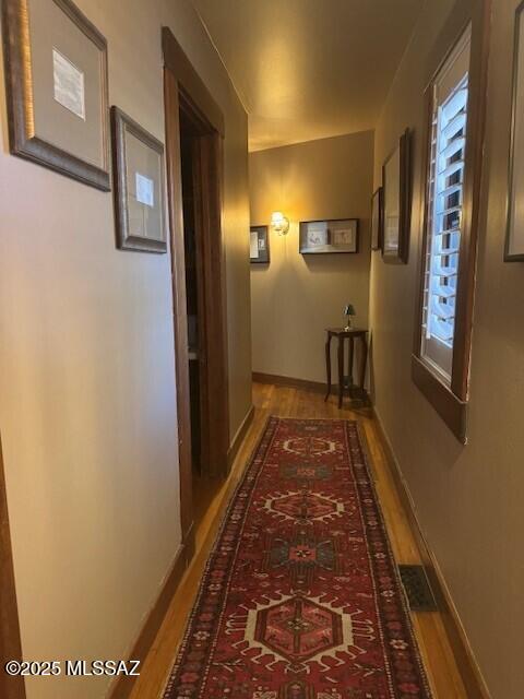 hallway featuring baseboards and wood finished floors