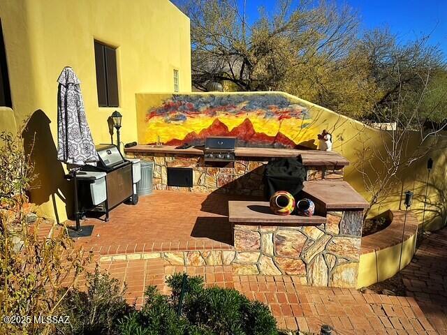 view of patio with exterior kitchen and a grill