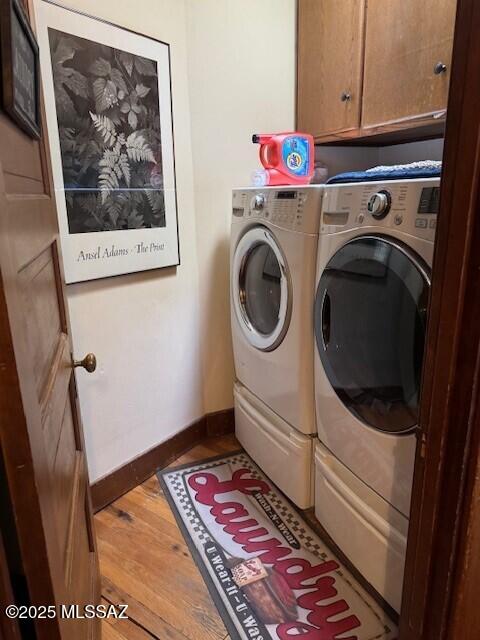 laundry area featuring baseboards, wood finished floors, cabinet space, and washer and dryer