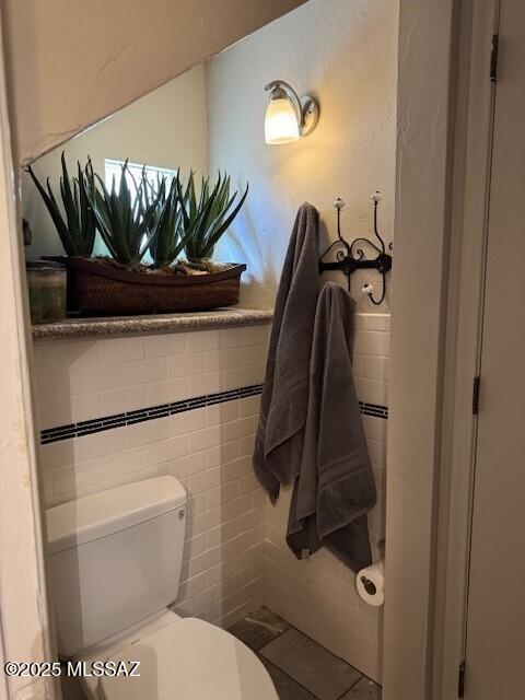 bathroom with tile walls, toilet, and tile patterned floors