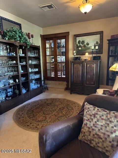 interior space featuring french doors, visible vents, and light carpet