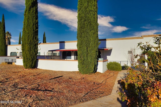 rear view of house with fence and stucco siding