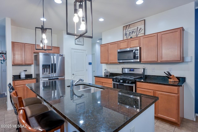 kitchen featuring a kitchen bar, light tile patterned floors, stainless steel appliances, a center island with sink, and a sink