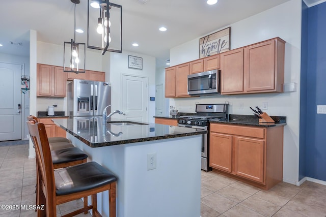 kitchen with a sink, dark stone counters, a kitchen breakfast bar, and appliances with stainless steel finishes