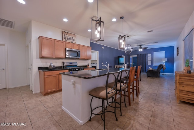 kitchen featuring a center island with sink, dark countertops, stainless steel appliances, light tile patterned floors, and visible vents