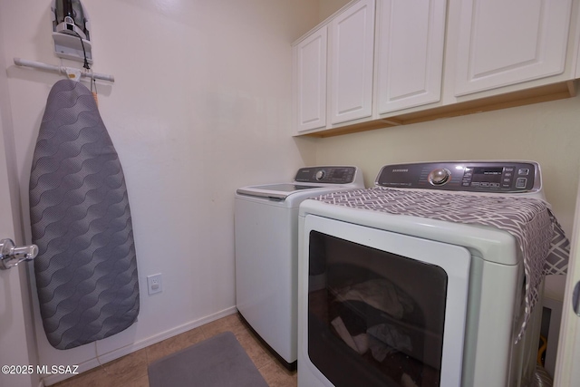 clothes washing area with tile patterned flooring, washer and clothes dryer, cabinet space, and baseboards