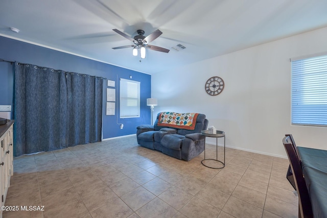 living area featuring tile patterned floors, visible vents, ceiling fan, and baseboards