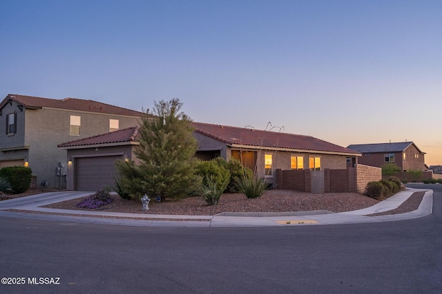 view of front of house with fence, a garage, stucco siding, a tile roof, and driveway