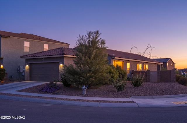 view of front of home with stucco siding, a tile roof, a garage, and driveway