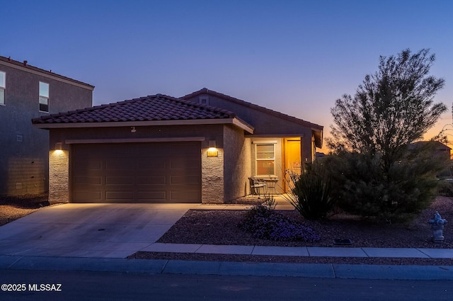 view of front of property featuring stucco siding, an attached garage, a tile roof, and concrete driveway