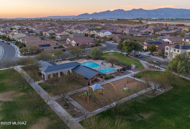 aerial view at dusk featuring a mountain view and a residential view