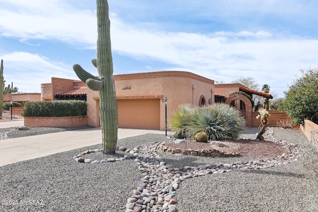 view of front of property featuring stucco siding, driveway, a garage, and fence