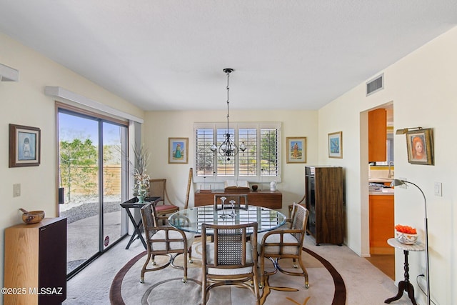 dining room with a wealth of natural light, visible vents, light carpet, and a notable chandelier