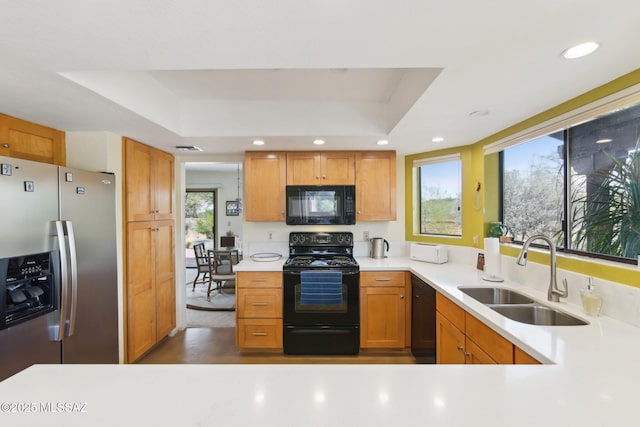 kitchen featuring a sink, a raised ceiling, black appliances, and light countertops