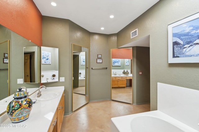 bathroom with vanity, a tub, recessed lighting, and visible vents