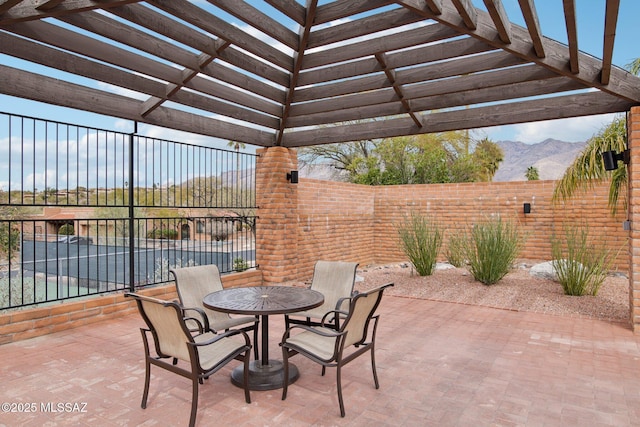 view of patio featuring outdoor dining area, a fenced backyard, a mountain view, and a pergola