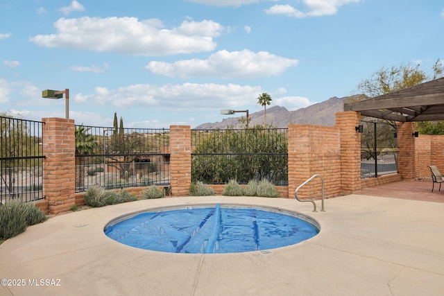 view of swimming pool featuring a patio, fence, and a mountain view