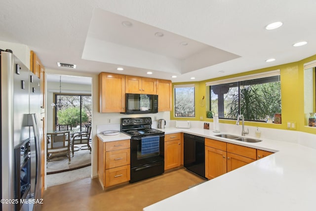 kitchen featuring a tray ceiling, recessed lighting, a sink, black appliances, and light countertops