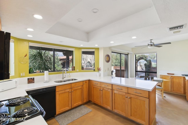 kitchen with visible vents, black appliances, a sink, a tray ceiling, and a peninsula