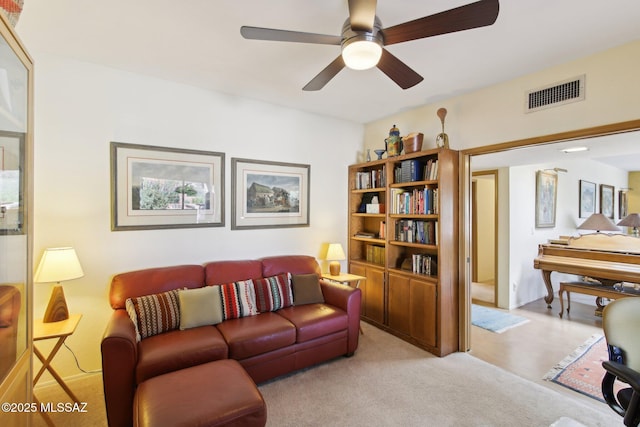 living area featuring visible vents, light carpet, and a ceiling fan