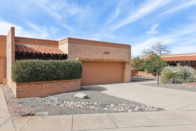 view of front of home with a tiled roof, stucco siding, driveway, and a garage