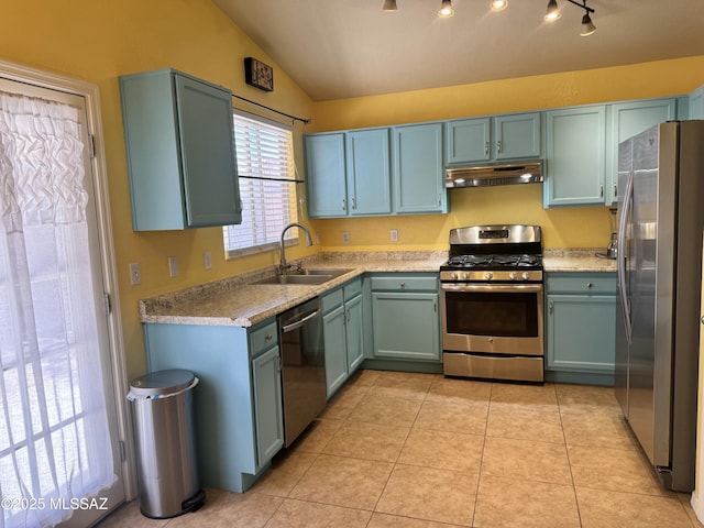 kitchen featuring lofted ceiling, light tile patterned floors, under cabinet range hood, a sink, and appliances with stainless steel finishes