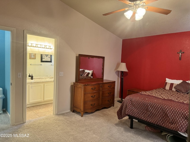 bedroom featuring baseboards, ensuite bath, a ceiling fan, and light colored carpet