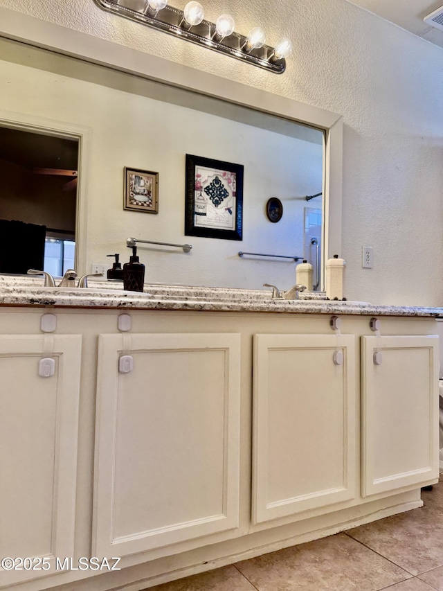 bathroom with a textured wall, tile patterned flooring, and visible vents