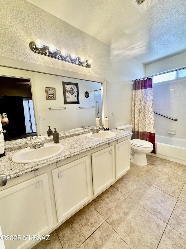 full bath featuring a textured ceiling, a sink, toilet, and tile patterned floors