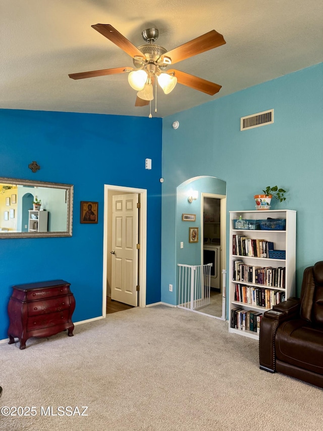 sitting room with carpet floors, ceiling fan, visible vents, and arched walkways