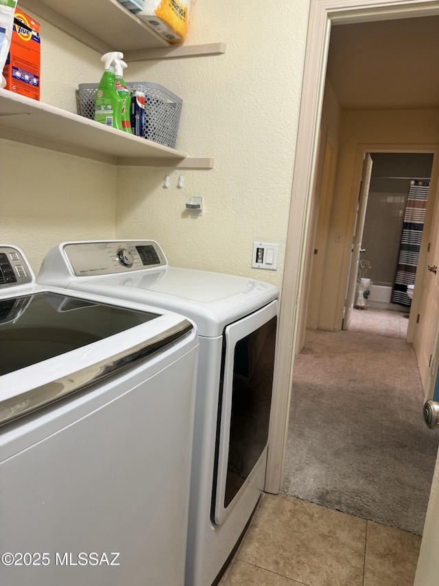 laundry room featuring light tile patterned floors, a textured wall, washing machine and dryer, light carpet, and laundry area