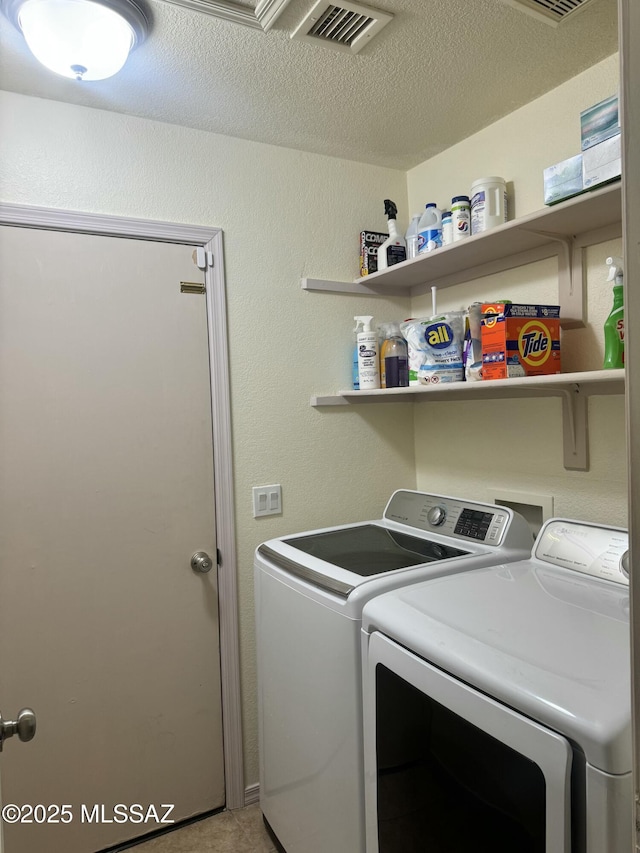 laundry room with a textured ceiling, a textured wall, laundry area, separate washer and dryer, and visible vents