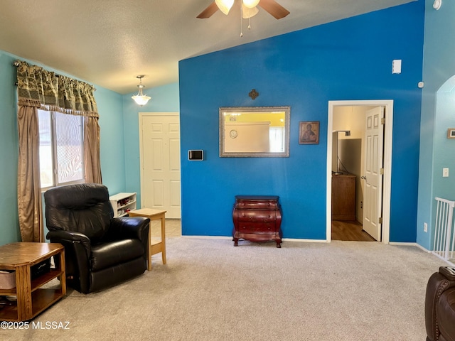 living area featuring carpet floors, ceiling fan, baseboards, and vaulted ceiling