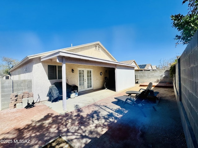 rear view of house with a patio area, french doors, a fenced backyard, and stucco siding