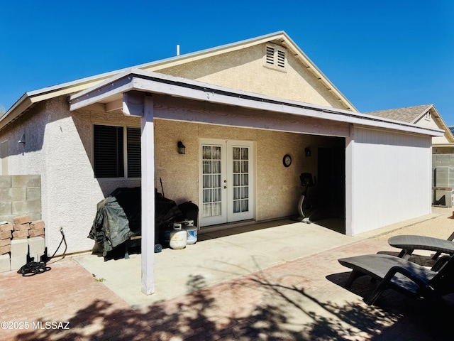 rear view of property featuring a patio, french doors, and stucco siding