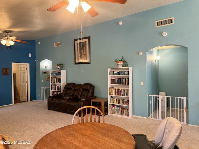 carpeted dining area featuring arched walkways, visible vents, and ceiling fan