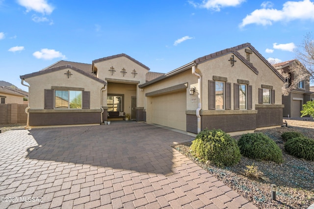 mediterranean / spanish home featuring a garage, decorative driveway, and stucco siding