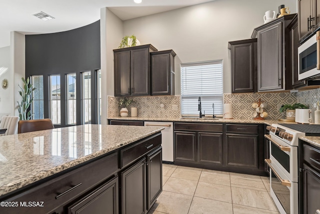 kitchen with light stone counters, a sink, visible vents, double oven range, and dishwasher